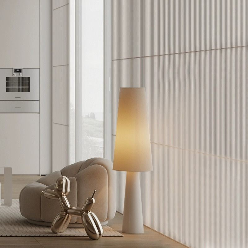 Lampadaire conique crème près d'un canapé
